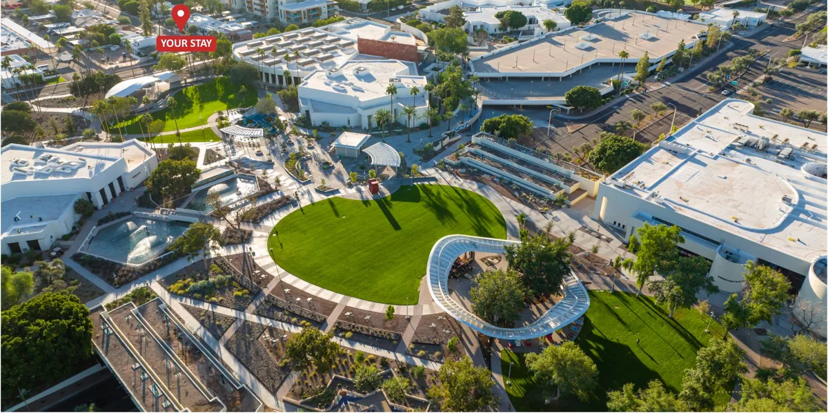 A modern property exterior featuring a lush green lawn, stylish architectural structures, an inviting pool area, seating arrangements, and landscaped pathways. The scene is buzzing with energy, suggesting both relaxation and opportunities for social gatherings.